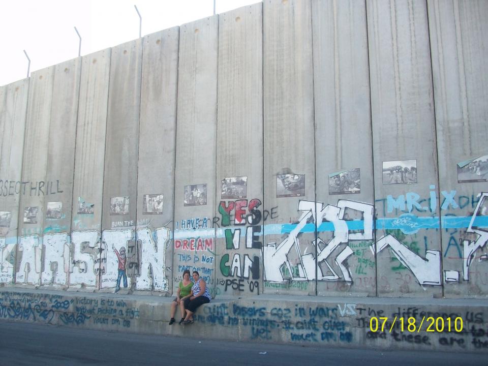 Sylvia Dahdal and her sister-in-law pose at the base of a section of the Separation Wall. / Courtesy photo