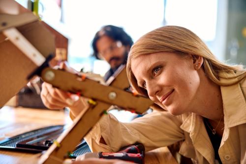 PhD in English student Amber Hedquist researches the use of AI in writing. In this ASU Thrive photo, she is working next to a person wearing safety glasses.