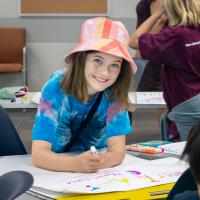 A young girl smiling and working on a YAWP project.